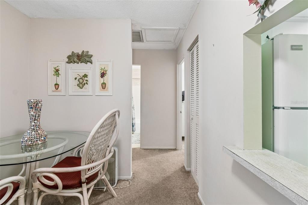 A dining area with a glass table and wicker chairs leads to a hallway — 6072 ARLENE WAY, BRADENTON, FL