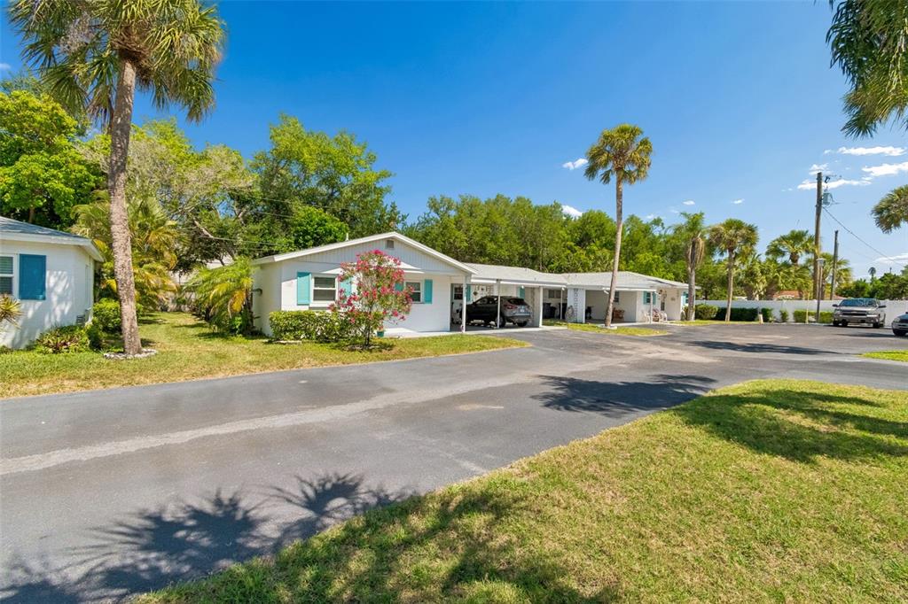 A row of single-story white houses with blue shutters and carports sits along a driveway — 6072 ARLENE WAY, BRADENTON, FL
