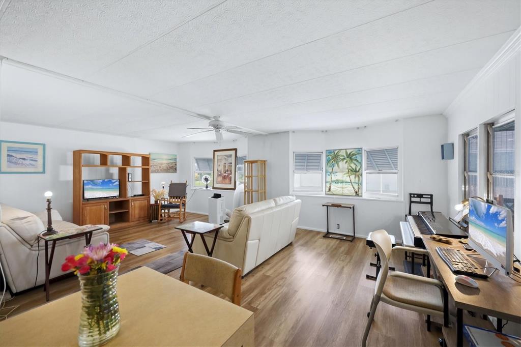 A living room features light wood flooring, a white sofa, and a desk with a computer — 4917 1ST A STREET E, BRADENTON, FL