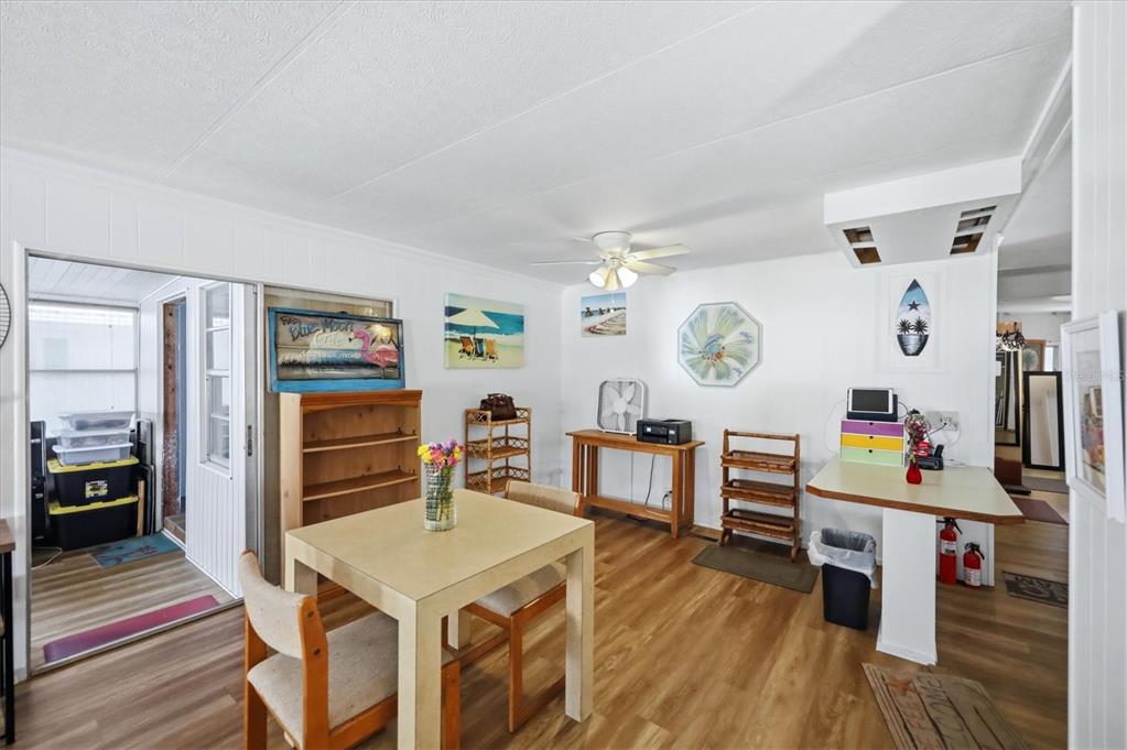 A dining area with light wood flooring, a square table, and various wall decorations — 4917 1ST A STREET E, BRADENTON, FL