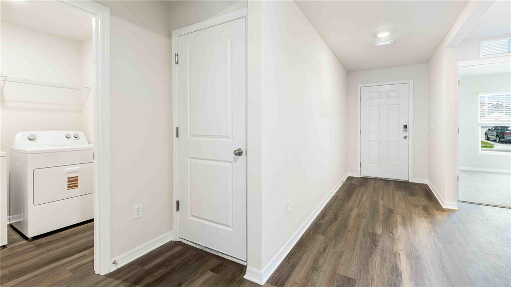 A laundry room with a washer and dryer sits beside a hallway with wood-look flooring — 10931 RABBIT GROVE TRAIL, PARRISH, FL