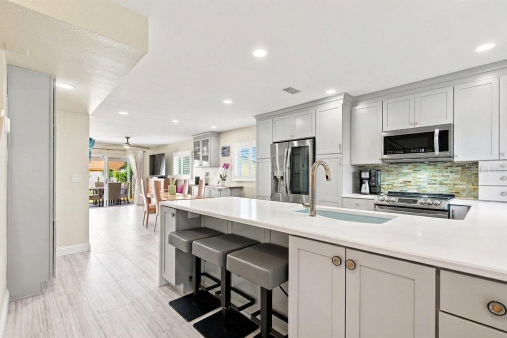 A kitchen with light gray cabinets, a white island, and bar stools, opening to a dining area — 245 116TH AVENUE UNIT 245, TREASURE ISLAND, FL