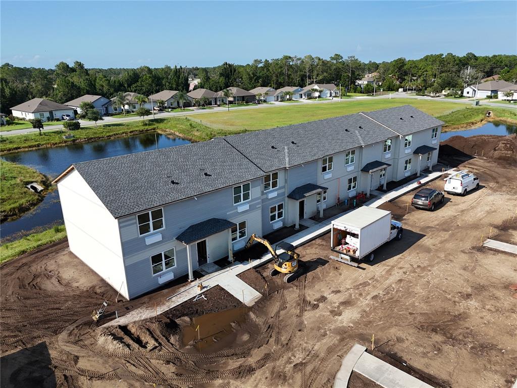 An aerial view shows a newly constructed multi-unit residential building surrounded by dirt and water — 34 GREEN CIRCLE UNIT 101, PALM COAST, FL