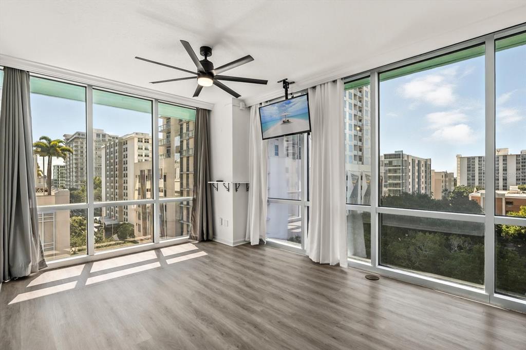 An empty room with wood-look flooring, a ceiling fan, and floor-to-ceiling windows overlooking city buildings — 322 E CENTRAL BOULEVARD UNIT 710, ORLANDO, FL
