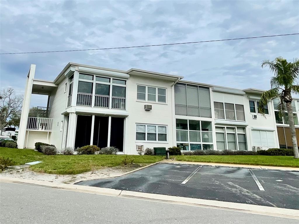 A two-story multi-unit residential building with screened balconies and a paved parking lot — 7050 SUNSET WAY UNIT 19, ST PETE BEACH, FL