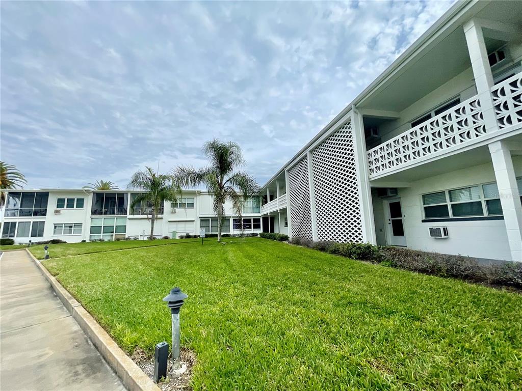 A low-rise apartment building with white exterior walls and a green lawn — 7050 SUNSET WAY UNIT 19, ST PETE BEACH, FL