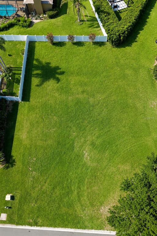 An aerial view shows a rectangular, grassy vacant lot bordered by white fencing and trees — 2116 LONGLEAF CIRCLE, LAKELAND, FL