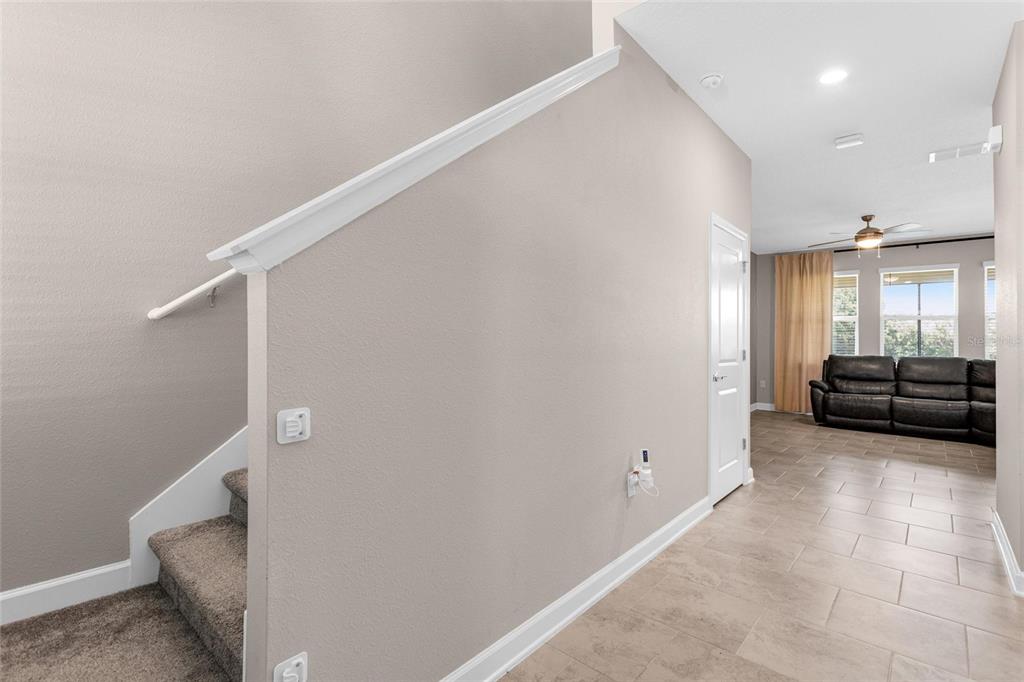 A view of a staircase with carpeted steps next to a tiled hallway and living area — 8833 BETH PAGE LN, DAVENPORT, FL