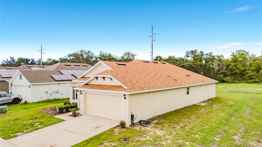 An exterior view of a beige suburban house with a tan shingled roof and garage — 843 CHINOY ROAD, DAVENPORT, FL