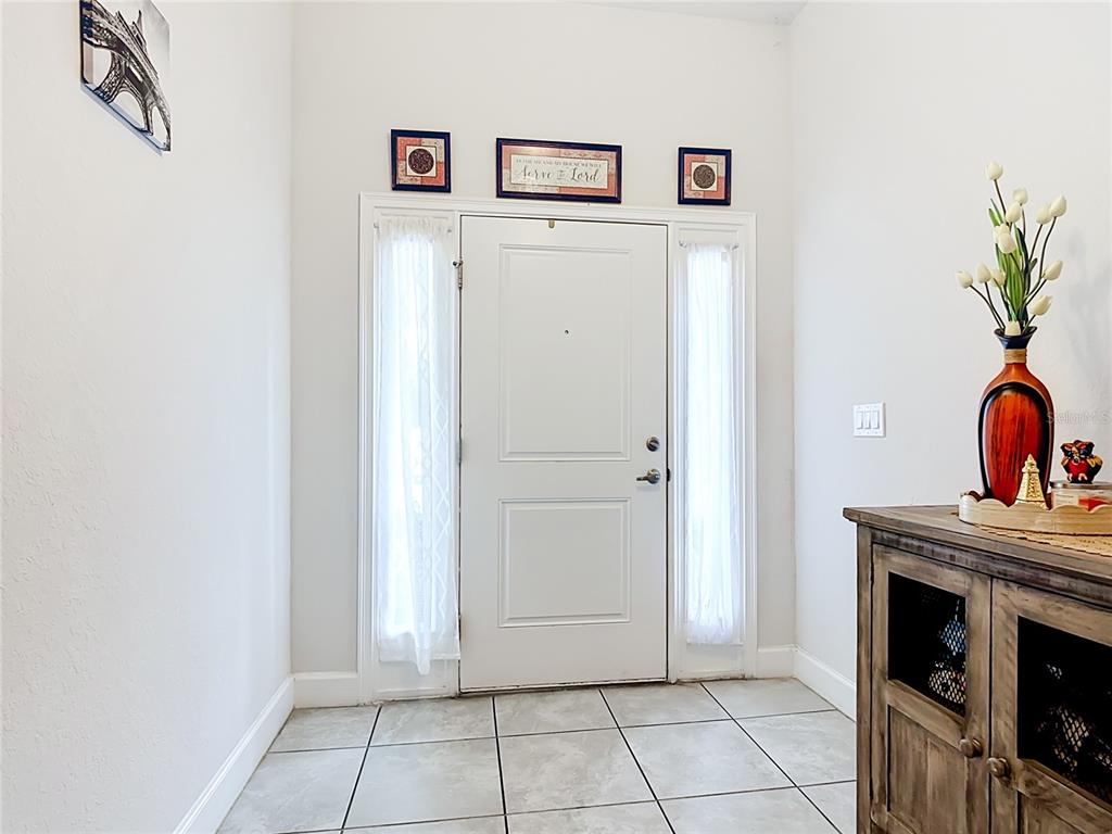 A tiled entryway features a white front door with sidelights and a wooden console table — 843 CHINOY ROAD, DAVENPORT, FL