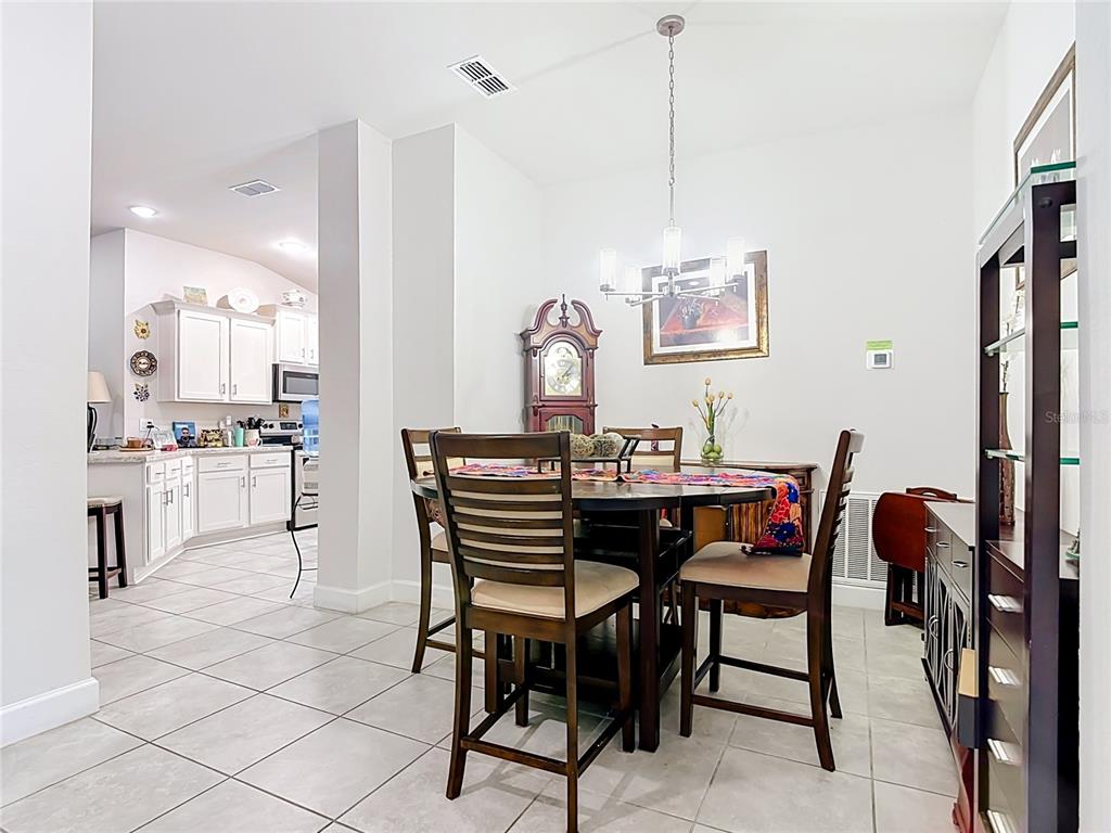 A dining area with a round table and chairs sits adjacent to an open kitchen — 843 CHINOY ROAD, DAVENPORT, FL