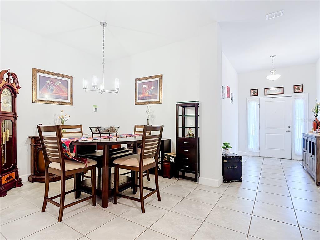A dining area with a wooden table and chairs sits adjacent to a tiled entryway — 843 CHINOY ROAD, DAVENPORT, FL