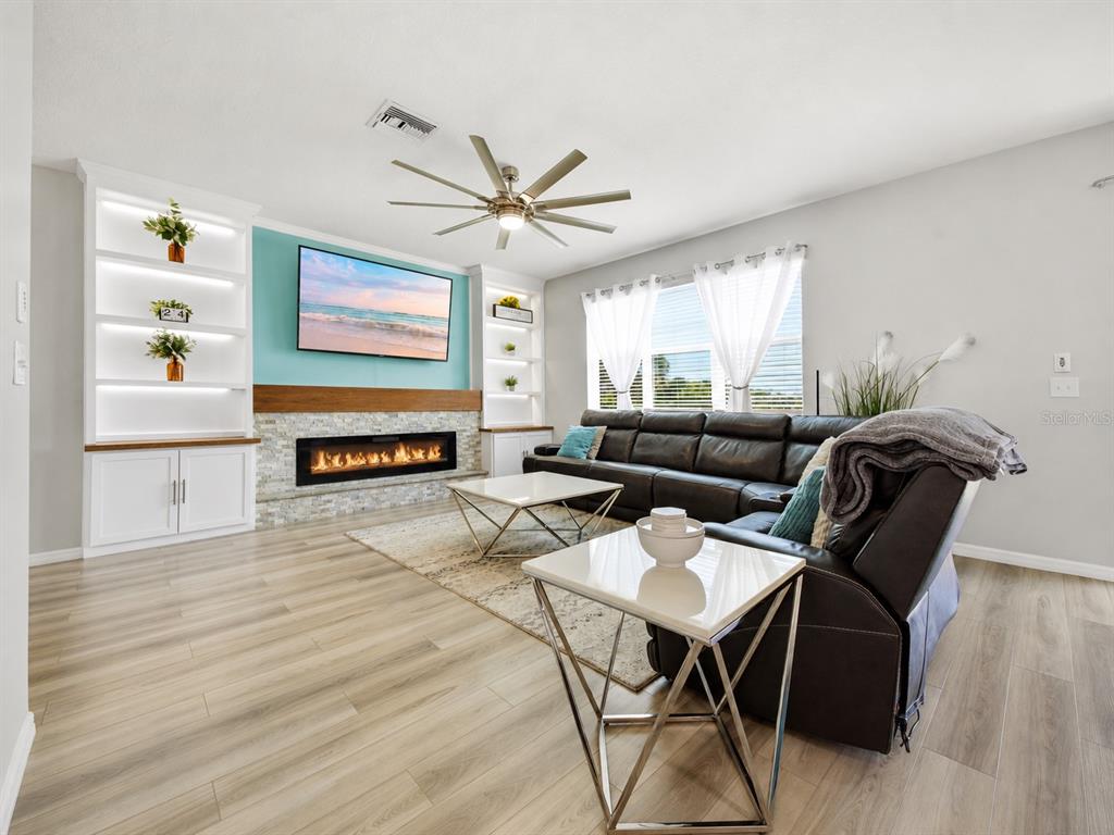 A living room features a fireplace, built-in shelving, a ceiling fan, and a leather sectional — 11520 GALLATIN TRAIL, PARRISH, FL