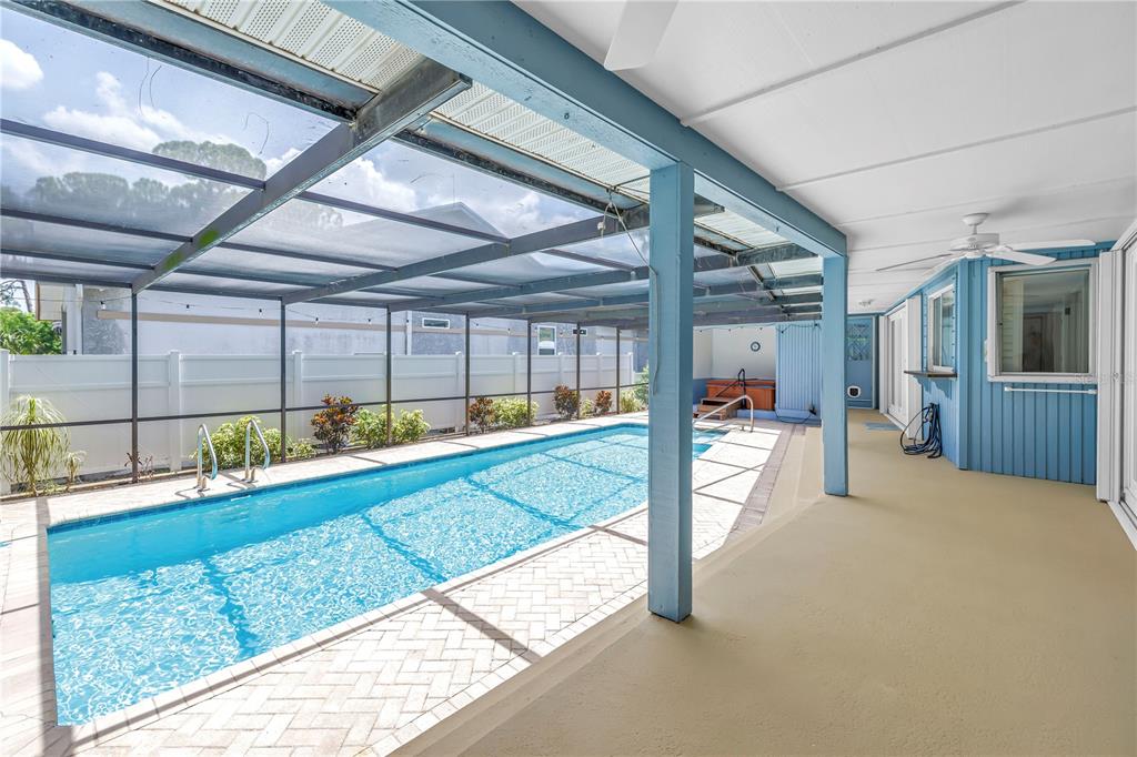 A covered patio overlooks a rectangular swimming pool enclosed by a screened-in lanai — 3000 HERON PLACE, CLEARWATER, FL