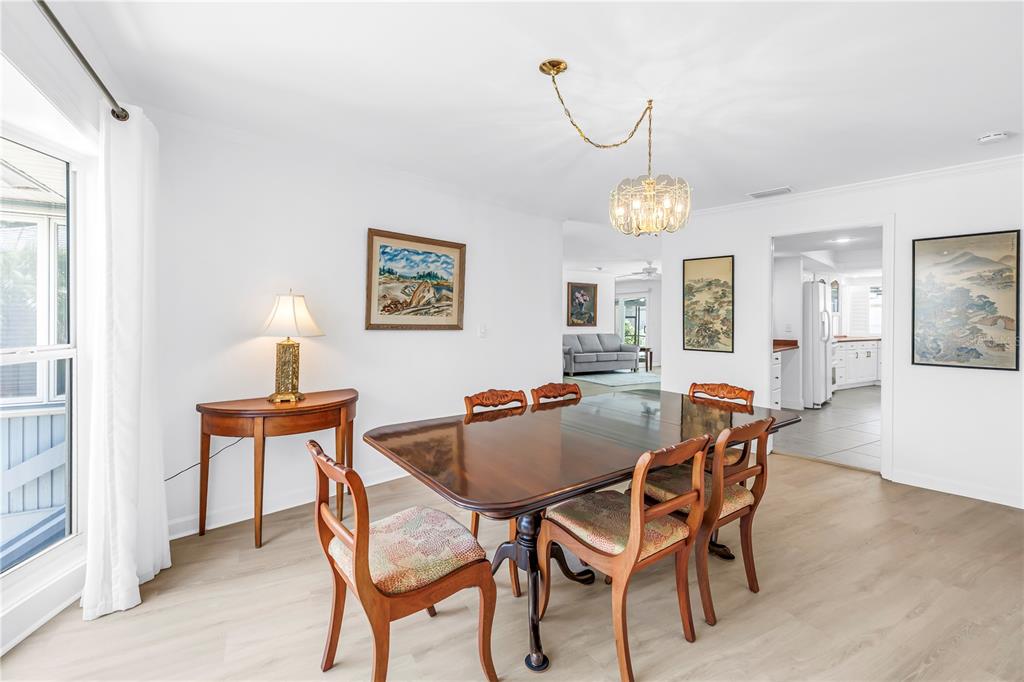 A dining room features a dark wood table with chairs, a chandelier, and light flooring — 3000 HERON PLACE, CLEARWATER, FL