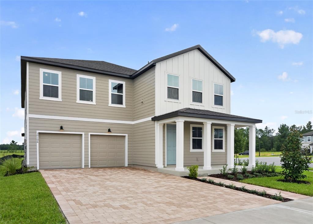 A two-story house with tan horizontal siding, white vertical siding, and a two-car garage — 30106 EMERALD FOREST DRIVE, MOUNT DORA, FL
