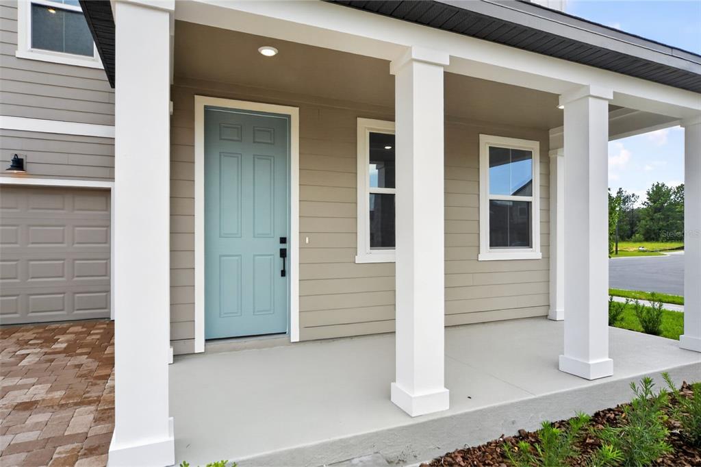 A light blue front door sits on a covered porch with white columns and siding — 30106 EMERALD FOREST DRIVE, MOUNT DORA, FL
