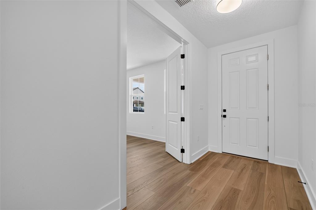 An entryway with light wood flooring leads to a room with double doors — 30106 EMERALD FOREST DRIVE, MOUNT DORA, FL