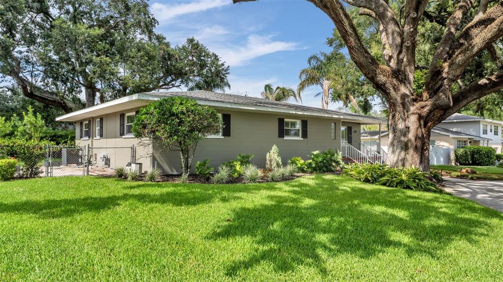 A single-story house with gray siding, a green lawn, and a large tree in front — 1522 DEL CREST PLACE, LAKELAND, FL