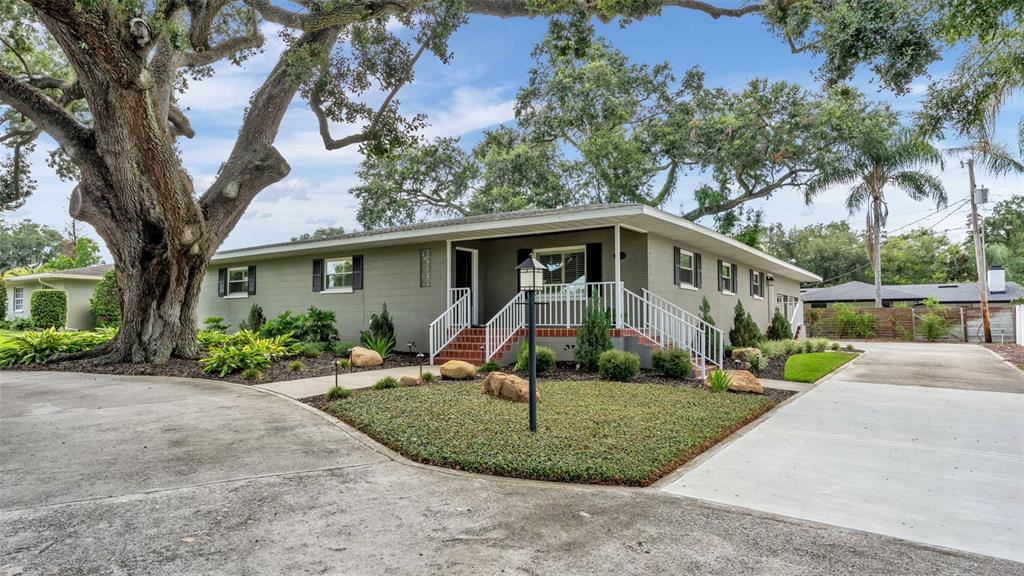 A single-story house with a gray brick exterior, white railings, and a large oak tree — 1522 DEL CREST PLACE, LAKELAND, FL