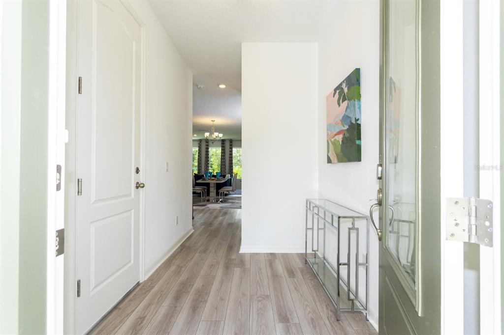 A bright entryway features light wood-look flooring, a glass console table, and a wall painting — 624 BENOI DRIVE, DAVENPORT, FL