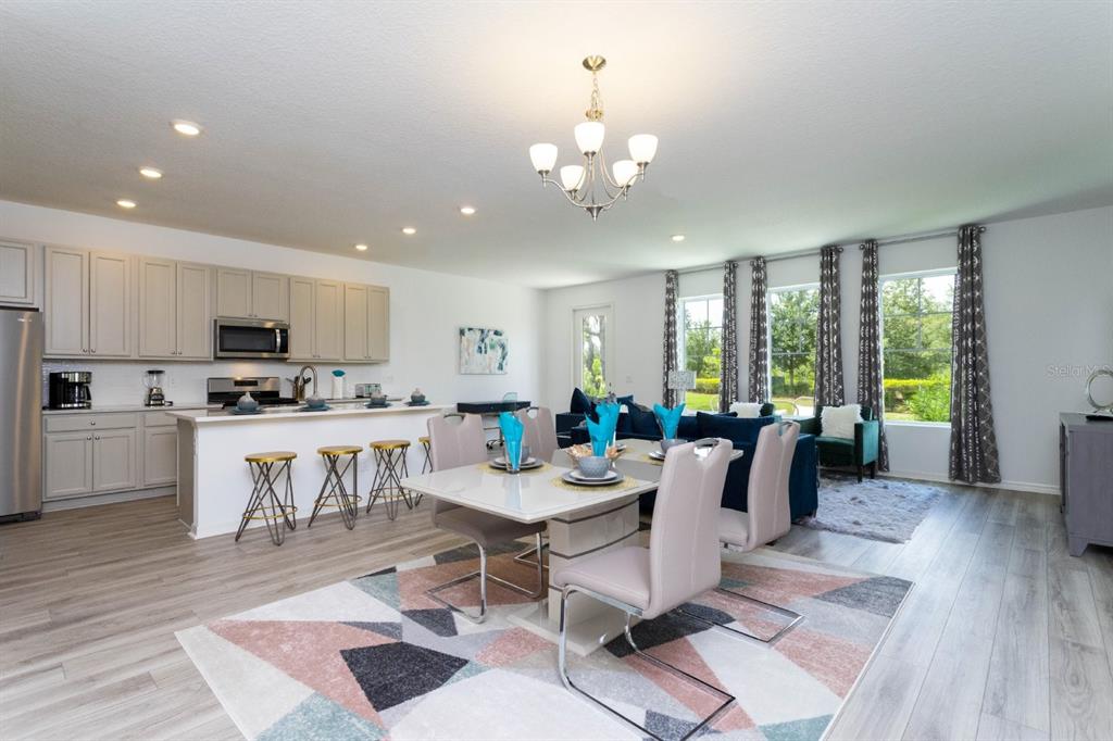 An open-concept kitchen and dining area features light gray cabinetry, a central island, and tile flooring — 624 BENOI DRIVE, DAVENPORT, FL