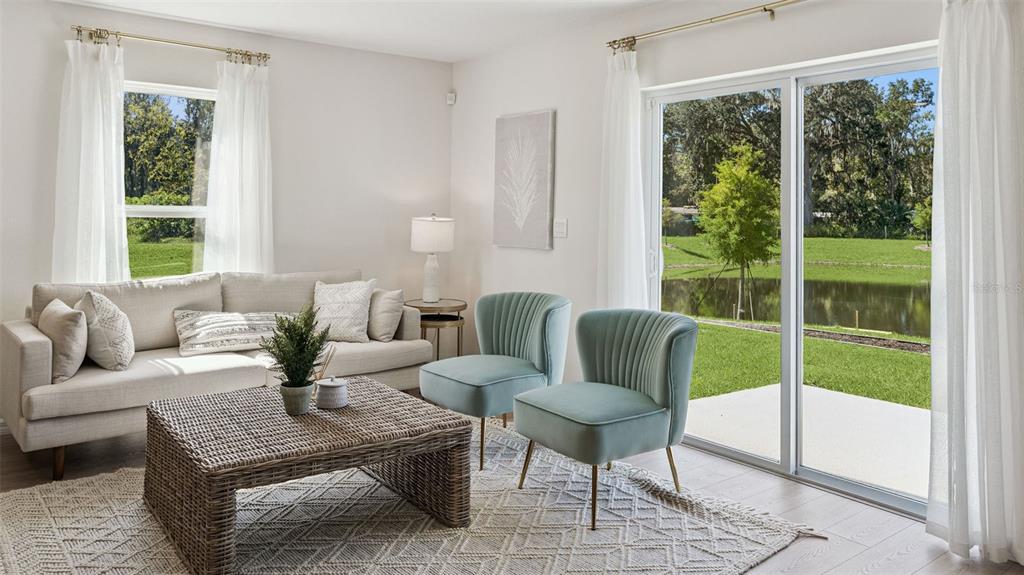 A living room features a beige sofa, two teal chairs, a wicker coffee table, and windows — 793 PRESTON COVE DRIVE, ST CLOUD, FL