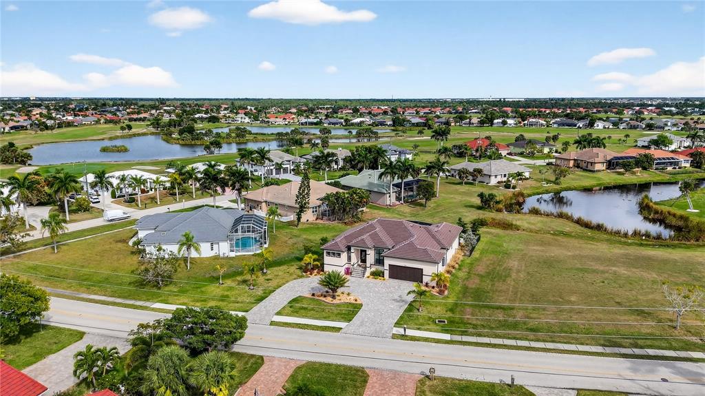 An aerial view shows a suburban neighborhood with houses, ponds, and green lawns — 609 MONACO DRIVE, PUNTA GORDA, FL