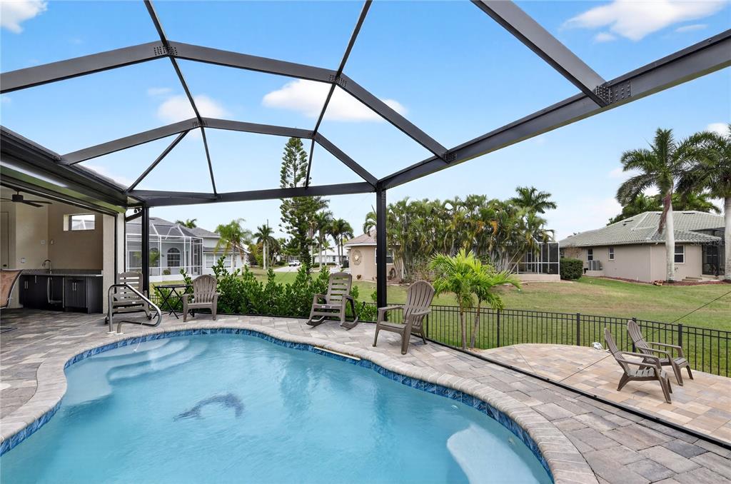A swimming pool with a screened-in patio and outdoor kitchen area in a backyard — 609 MONACO DRIVE, PUNTA GORDA, FL