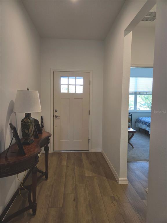 An entryway features a wood-look tile floor, a console table with a lamp, and a door — 3995 CAYMAN DRIVE, TITUSVILLE, FL