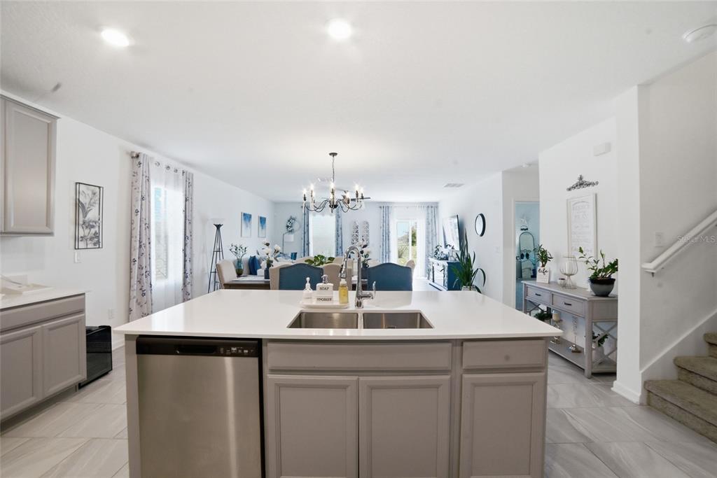 A kitchen island with a stainless steel dishwasher and sink faces an open dining area — 4980 FOUR STRAND COURT, ST CLOUD, FL