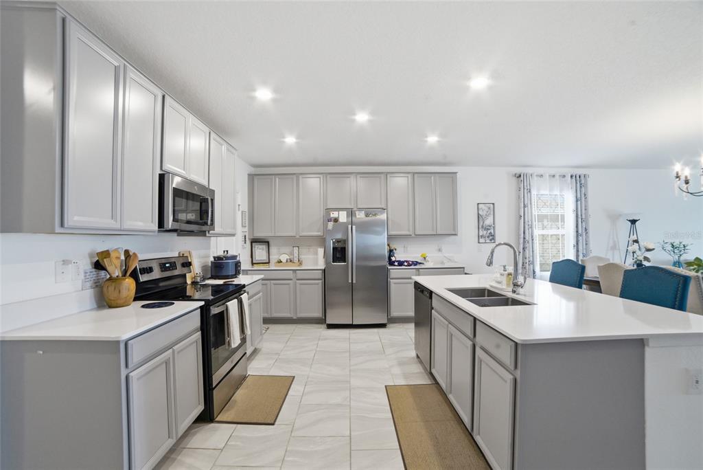 A kitchen featuring grey cabinets, stainless steel appliances, white countertops, and light-colored tile flooring — 4980 FOUR STRAND COURT, ST CLOUD, FL