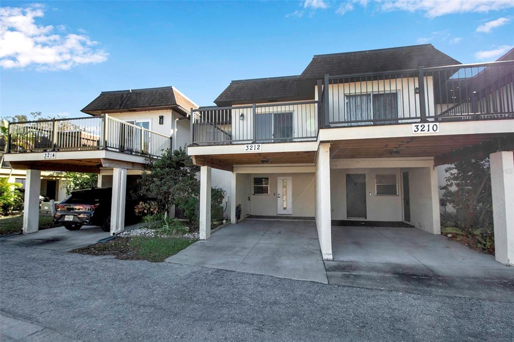 The exterior view shows two-story townhomes with elevated balconies and ground-level covered parking spaces — 3212 RAMBLEWOOD DRIVE N UNIT 3212, SARASOTA, FL