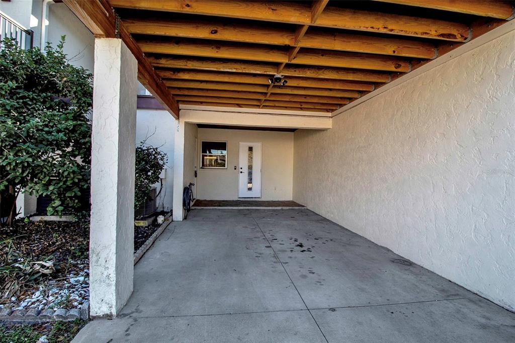 A covered concrete carport leads to a white front door and a small window — 3212 RAMBLEWOOD DRIVE N UNIT 3212, SARASOTA, FL
