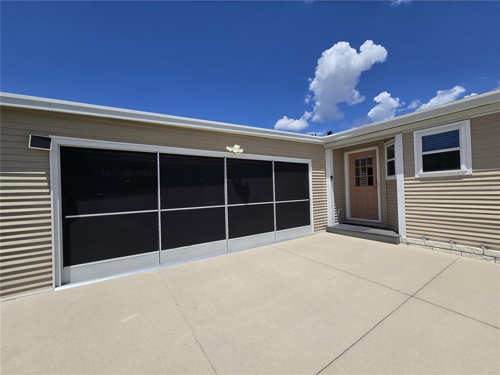 A beige-sided house exterior features a screened-in garage opening and a tan entry door — 4139 GREENBLUFF COURT UNIT 795, ZELLWOOD, FL