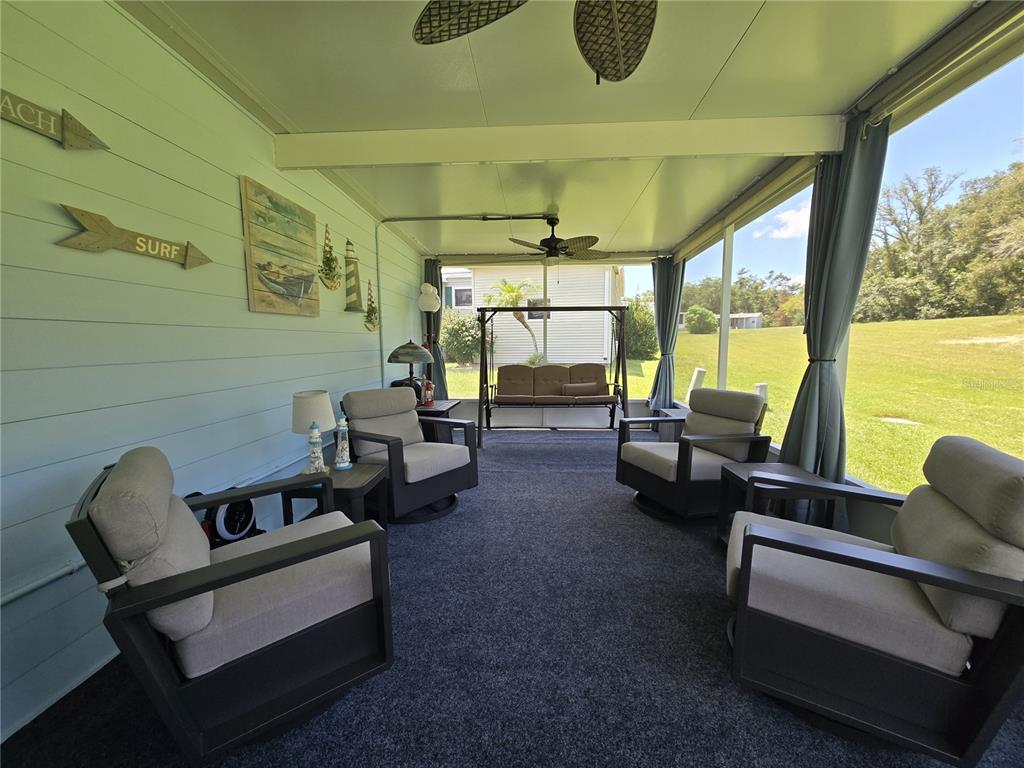 A screened-in porch features four armchairs, a swing, and light blue horizontal wall siding — 4139 GREENBLUFF COURT UNIT 795, ZELLWOOD, FL