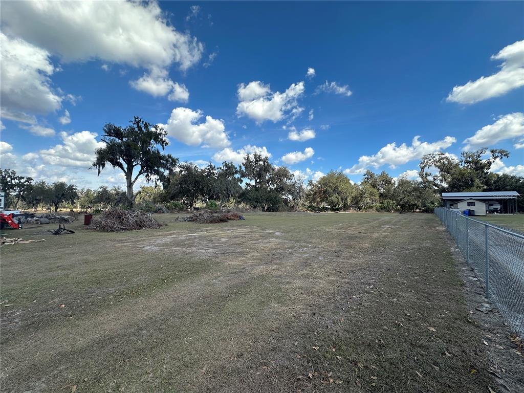 A large, grassy, open lot features scattered piles of brush and mature trees — 9988 BRYANT ROAD, LITHIA, FL