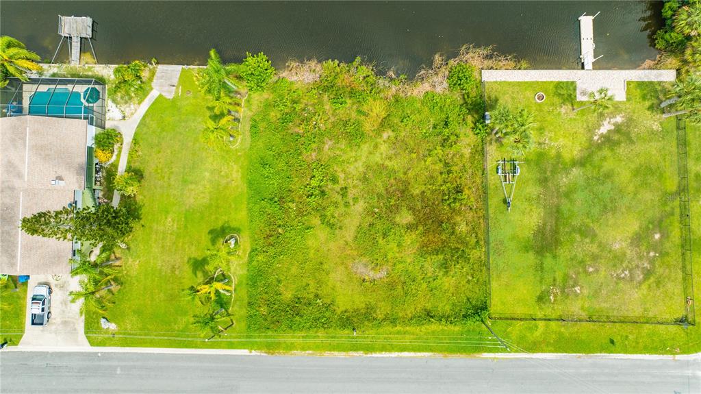An aerial view shows a vacant, grassy residential lot situated between two developed waterfront properties — 3326 FERNLEAF DRIVE, HERNANDO BEACH, FL