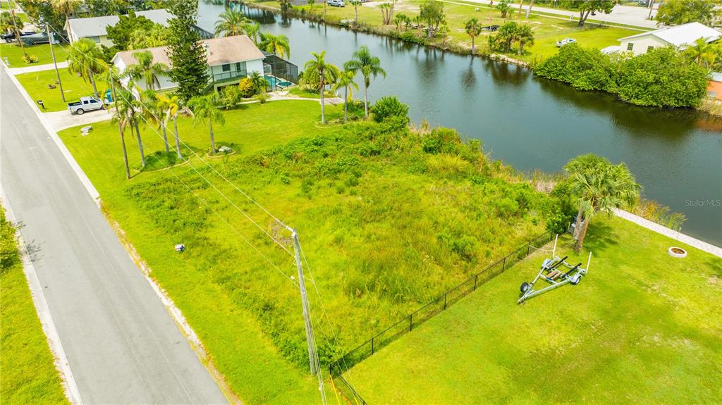 An aerial view shows a vacant, grassy residential lot situated between a road and a canal — 3326 FERNLEAF DRIVE, HERNANDO BEACH, FL