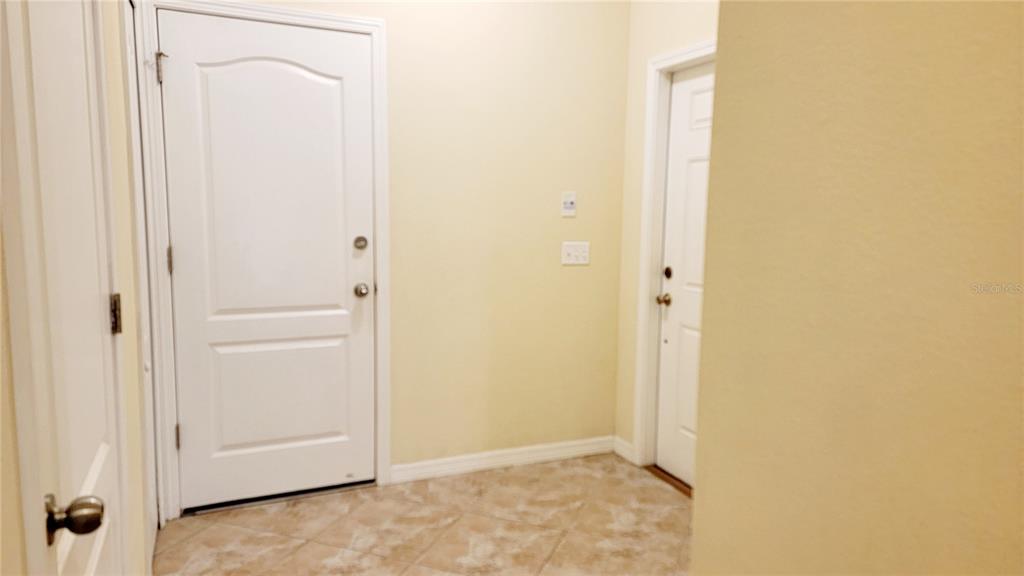 An interior entryway features tile flooring, two white doors, and light-colored walls — 9540 TRUMPET VINE LOOP, TRINITY, FL