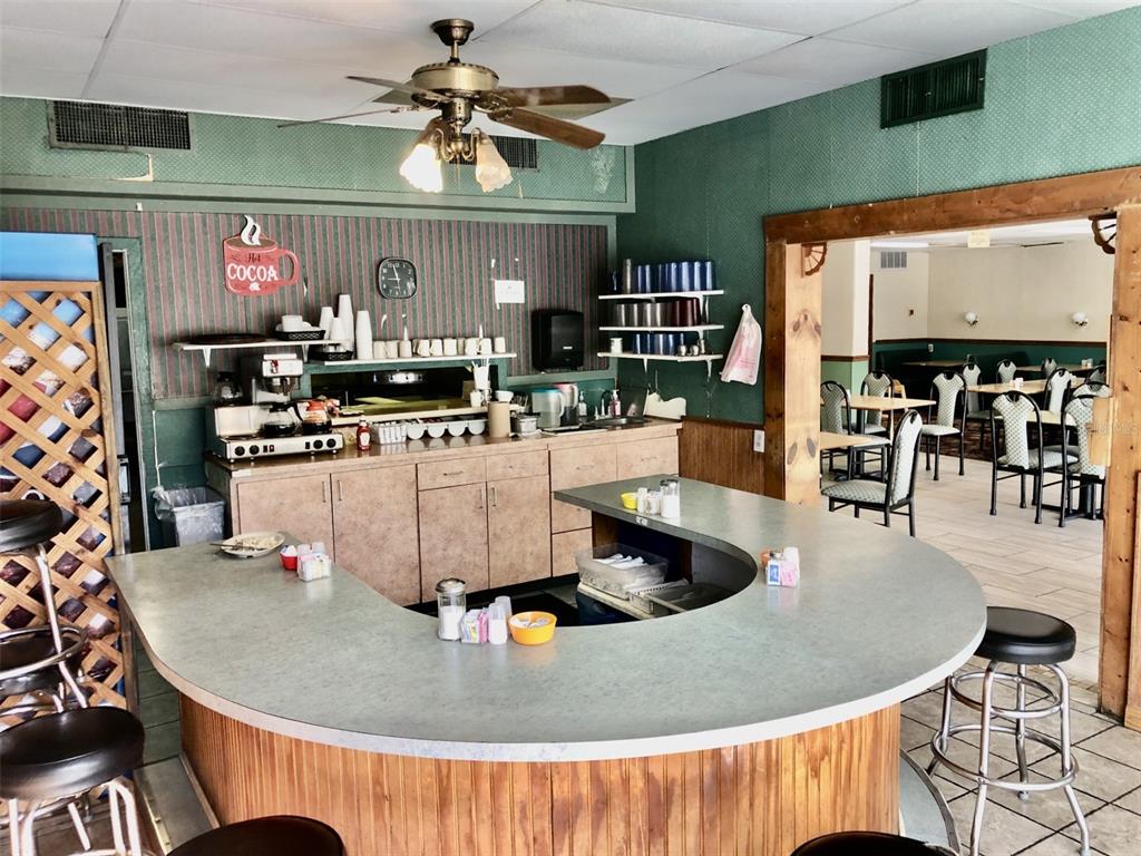 A diner interior features a curved service counter, stools, and an adjacent dining area — 1726 N FORT HARRISON AVENUE, CLEARWATER, FL