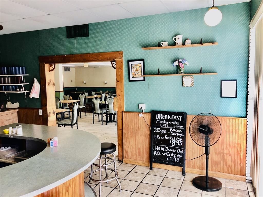 A diner interior features a curved counter, a chalkboard menu, and a doorway to seating — 1726 N FORT HARRISON AVENUE, CLEARWATER, FL