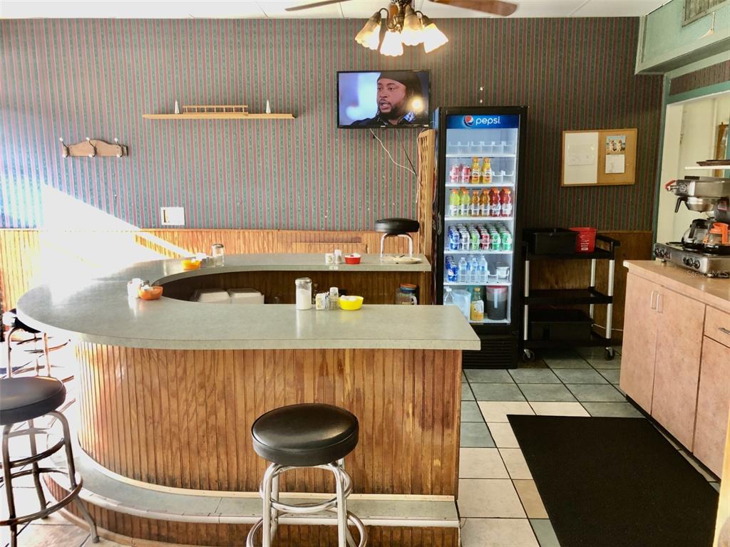A curved wooden bar with stools sits in a room with striped wallpaper and flooring — 1726 N FORT HARRISON AVENUE, CLEARWATER, FL