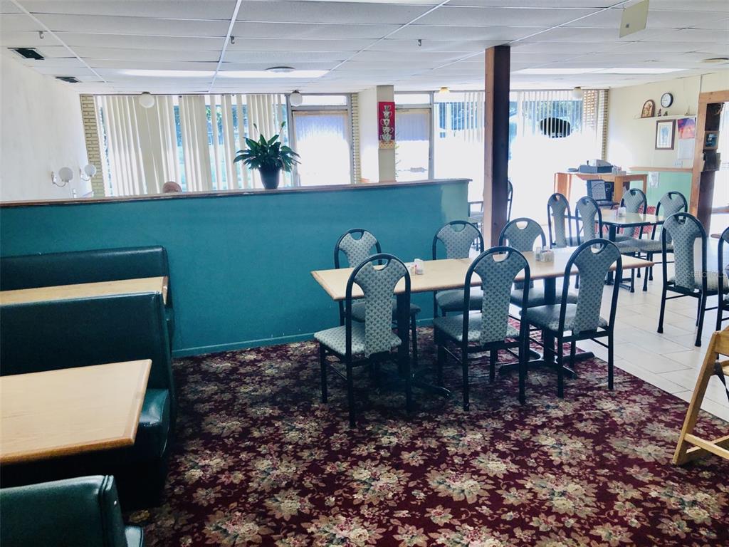 A restaurant dining area features floral carpet, teal walls, booth seating, and several tables — 1726 N FORT HARRISON AVENUE, CLEARWATER, FL