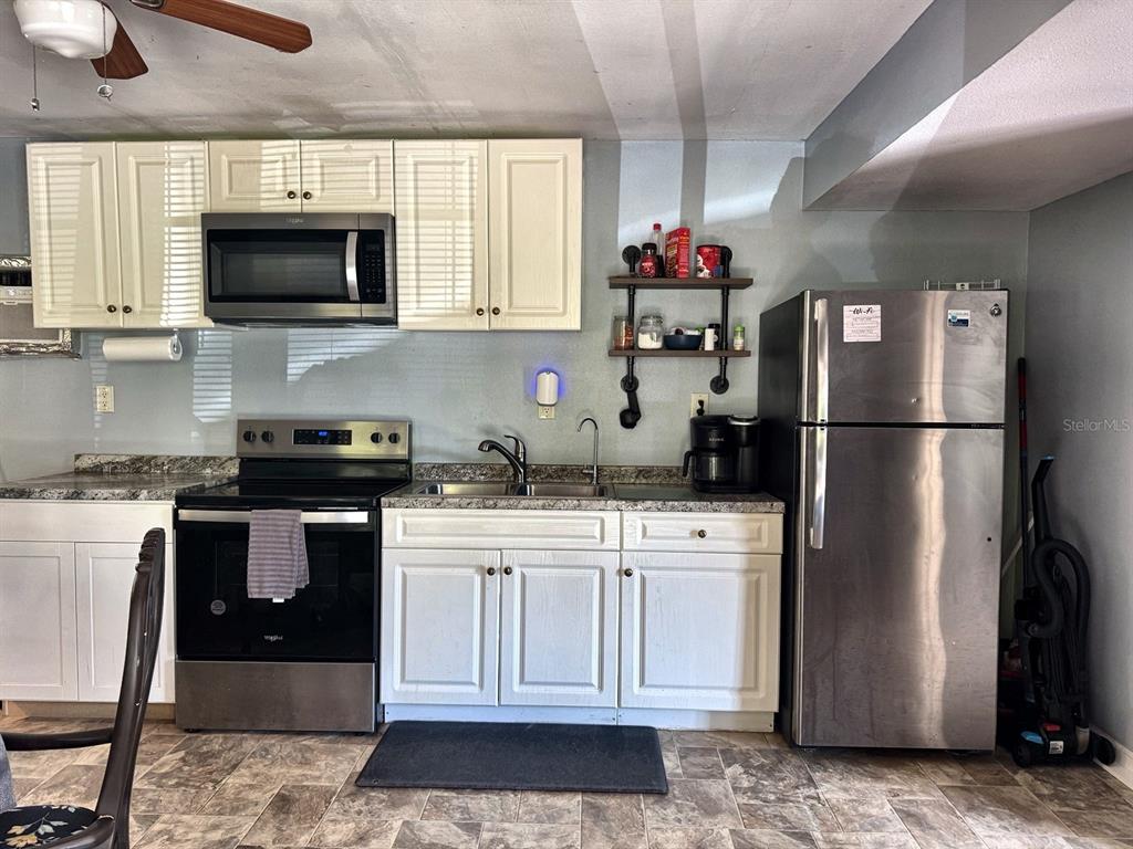 A kitchen features white cabinets, stainless steel appliances, a sink, and a wall-mounted shelf — 6838 N CARL G ROSE HIGHWAY, HERNANDO, FL
