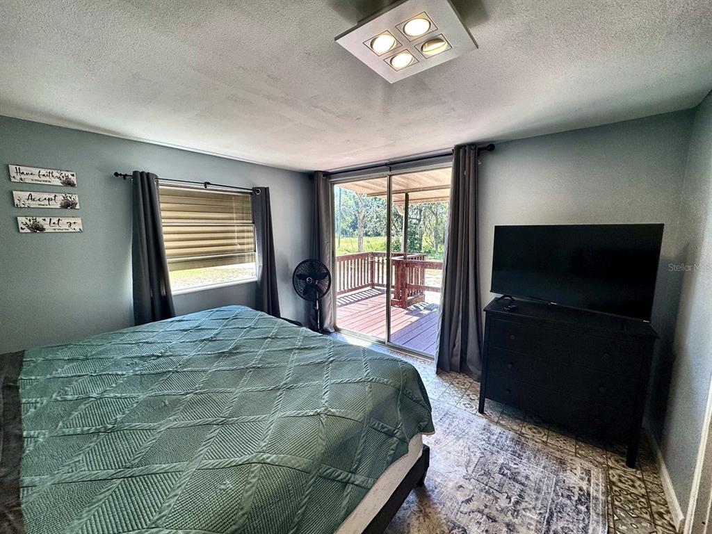 A bedroom features a bed, a dresser with a television, and a sliding door to a deck — 6838 N CARL G ROSE HIGHWAY, HERNANDO, FL