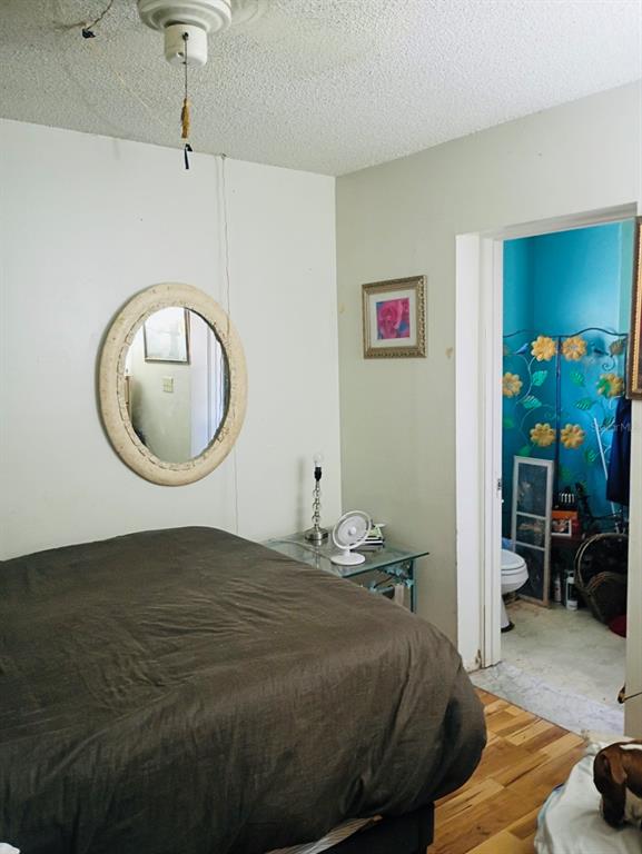 A bedroom with a brown bed, a round mirror, and an open doorway to a bathroom — 27043 ROPER ROAD, BROOKSVILLE, FL