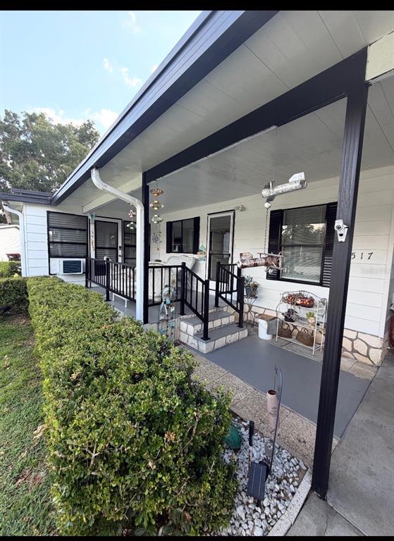 A single-story white house with a metal roof, large windows, and a concrete driveway — 6517 SE 110TH LANE, BELLEVIEW, FL