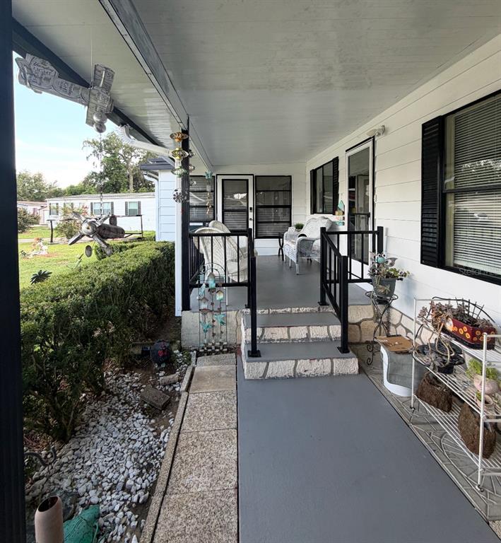 A white mobile home features a covered front porch, a hedge, and lawn ornaments — 6517 SE 110TH LANE, BELLEVIEW, FL