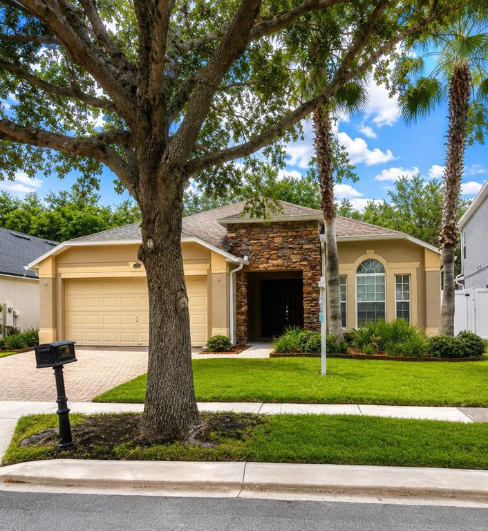 A single-story house with a stone facade, a two-car garage, and a large front tree — 11513 MOSSY OAK DRIVE, ORLANDO, FL
